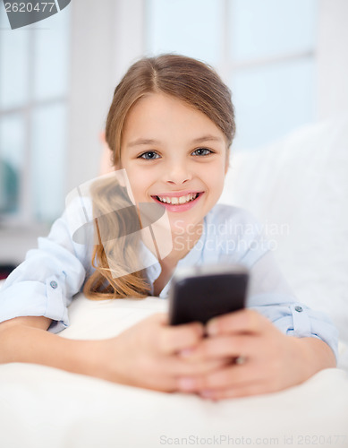 Image of smiling girl with smartphone at home