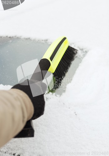 Image of closeup of man cleaning snow from car