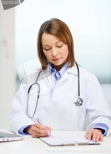 Image of busy doctor with laptop computer and clipboard