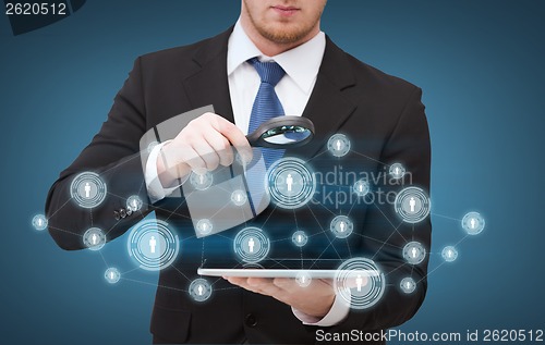 Image of businessman hand holding magnifier over tablet pc