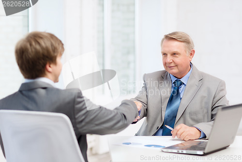 Image of older man and young man shaking hands in office