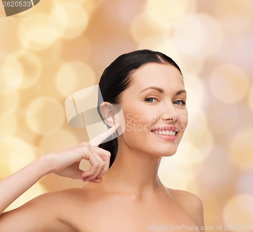 Image of young calm woman pointing to her ear