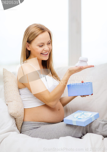 Image of smiling pregnant woman with gift box and bootees