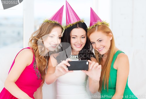 Image of three smiling women in hats having fun with camera