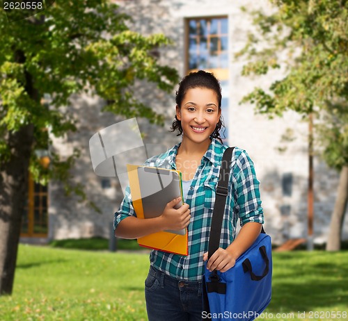 Image of smiling student with folders, tablet pc and bag