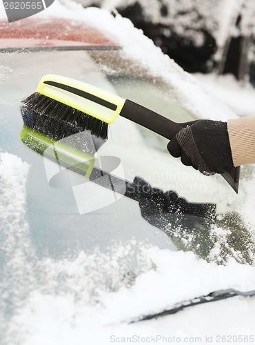 Image of closeup of man cleaning snow from car