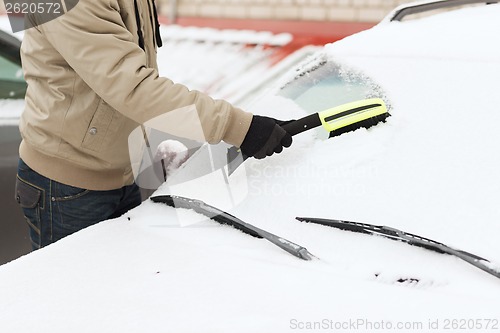 Image of closeup of man cleaning snow from car