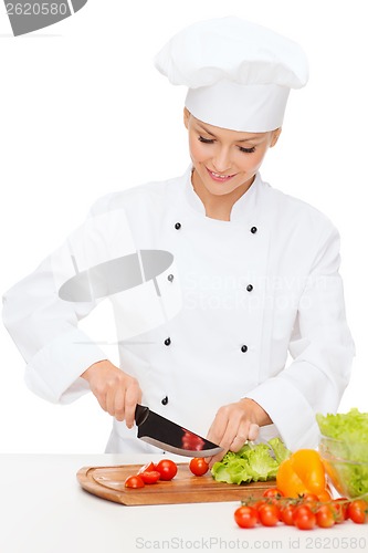 Image of smiling female chef chopping vagetables