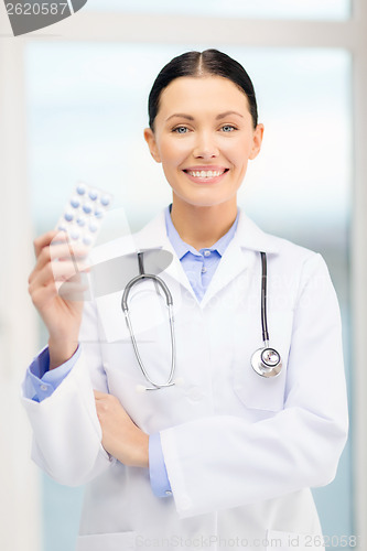 Image of smiling young doctor with pills and sthethoscope