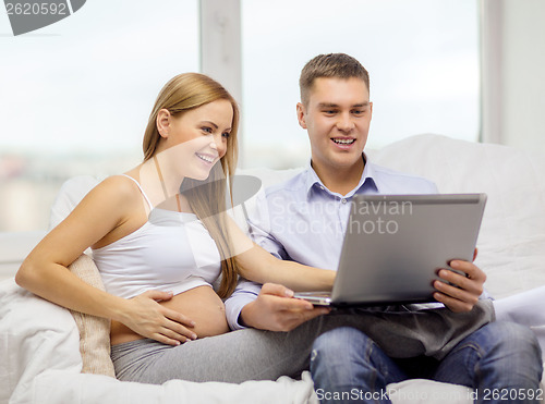 Image of expecting family with laptop computer