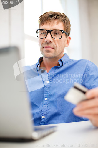 Image of man with laptop and credit card at home