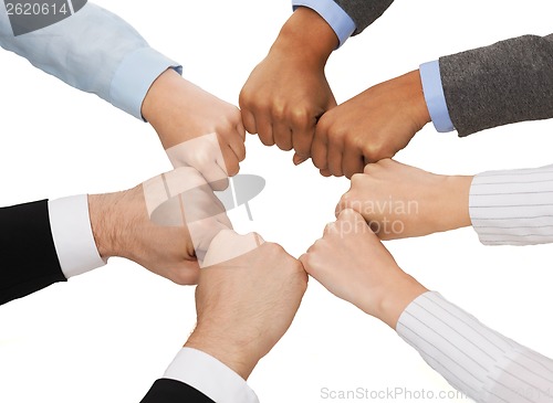 Image of closeup of businesspeople hands in fists in circle