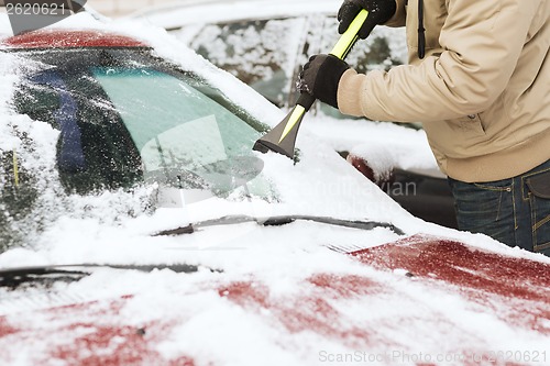 Image of closeup of man scraping ice from car