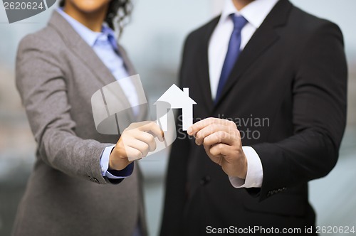 Image of businessman and businesswoman holding white house