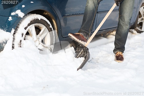 Image of closeup of man digging up stuck in snow car