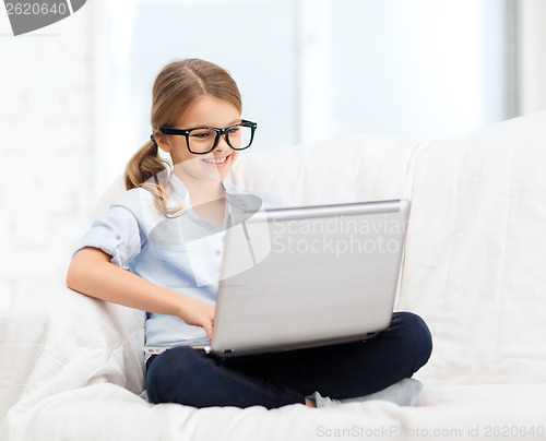 Image of smiling girl in specs with laptop computer at home