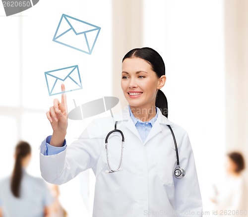 Image of smiling female doctor pointing to envelope