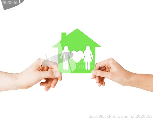 Image of hands holding green house with family