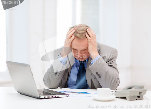 Image of upset older businessman with laptop and telephone