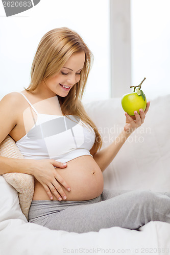 Image of happy pregnant woman with fresh green apple