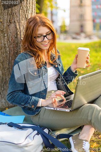 Image of teenager in eyeglasses with laptop and coffee