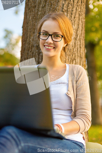 Image of smiling teenager in eyeglasses with laptop