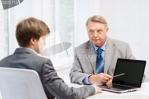 Image of older man and young man with laptop computer