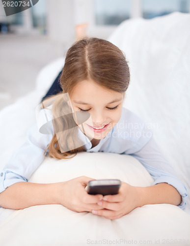 Image of smiling girl with smartphone at home