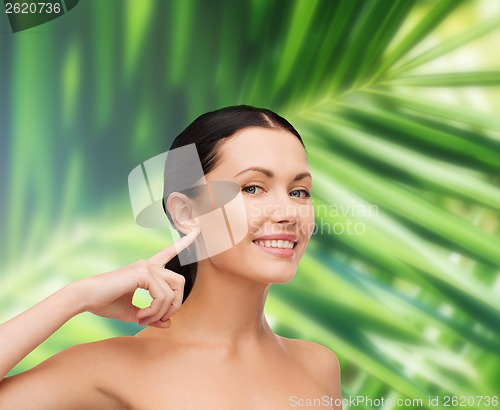 Image of young calm woman pointing to her ear