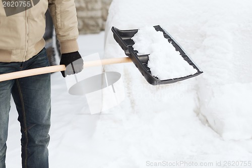 Image of closeup of man shoveling snow from driveway