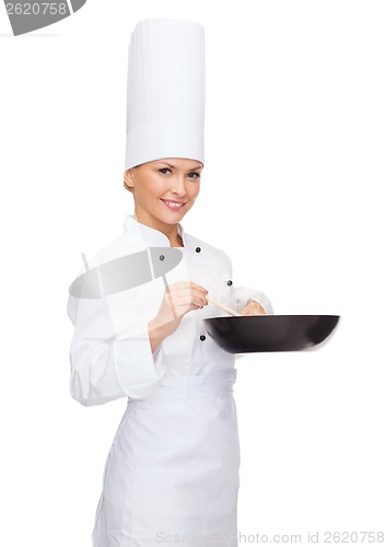 Image of smiling female chef with pan and spoon