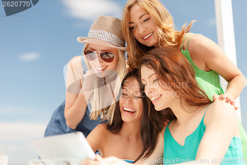 Image of smiling girls looking at tablet pc in cafe