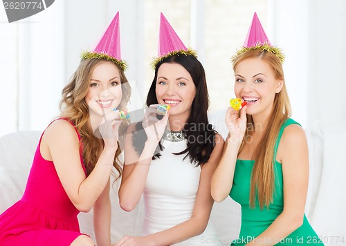 Image of three smiling women in hats blowing favor horns