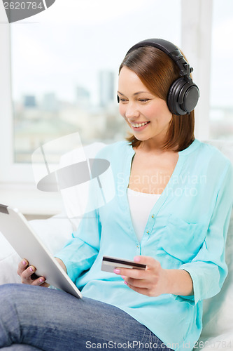 Image of happy woman with tablet pc and credit card at home
