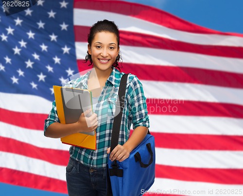 Image of smiling student with folders, tablet pc and bag