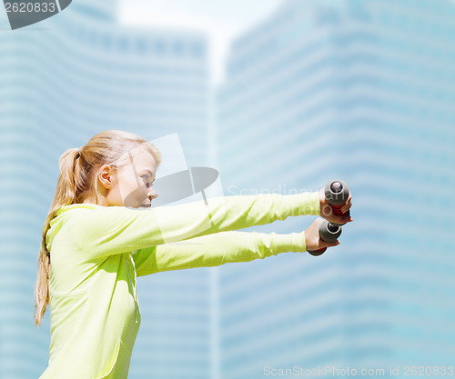 Image of sporty woman with light dumbbells outdoors