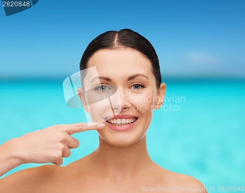 Image of young calm woman pointing to her mouth