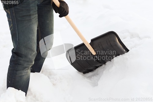 Image of closeup of man shoveling snow from driveway