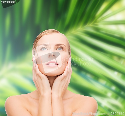 Image of beautiful woman touching her face and looking up