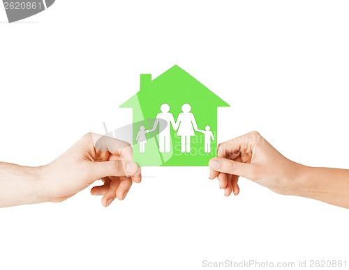 Image of hands holding green house with family