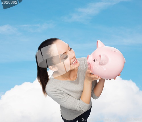 Image of happy woman looking at piggy bank