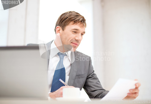 Image of businessman with laptop computer and documents