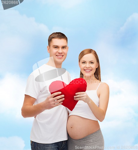 Image of happy young family expecting child with big heart
