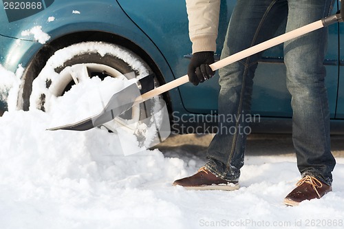 Image of closeup of man digging up stuck in snow car