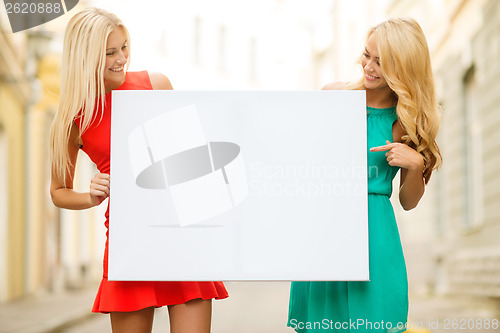 Image of two happy blonde women with blank white board