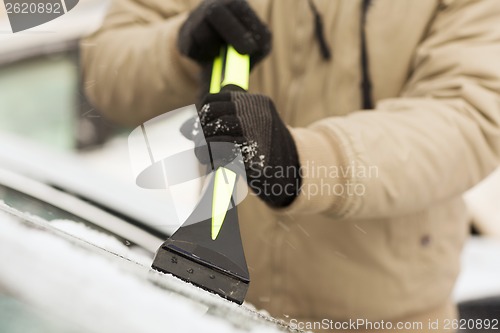 Image of closeup of man scraping ice from car