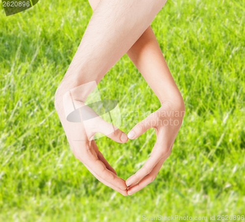 Image of woman and man hands showing heart shape