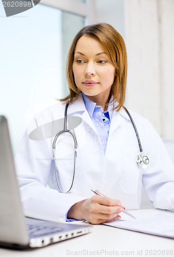 Image of busy doctor with laptop computer and clipboard