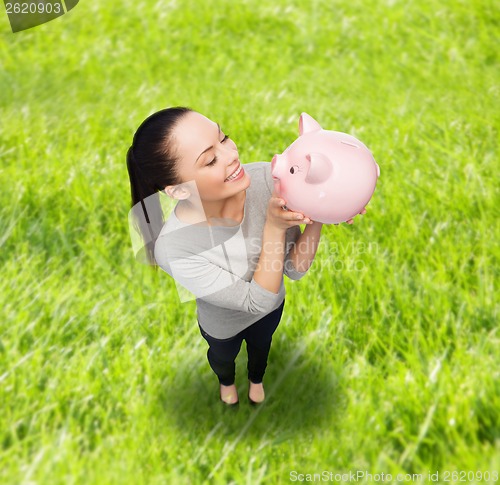 Image of happy woman looking at piggy bank