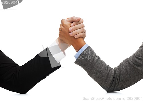 Image of businessman and businesswoman wrestling on table